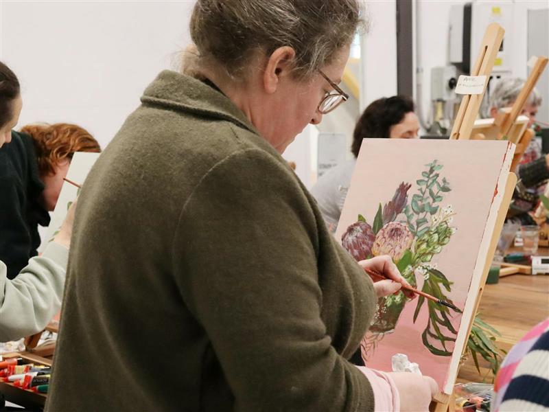 A female painitng a botanical still life from fresh botanicals