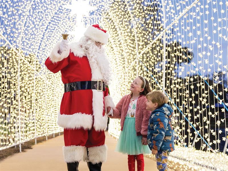 Santa and two children under a sparkling archway
