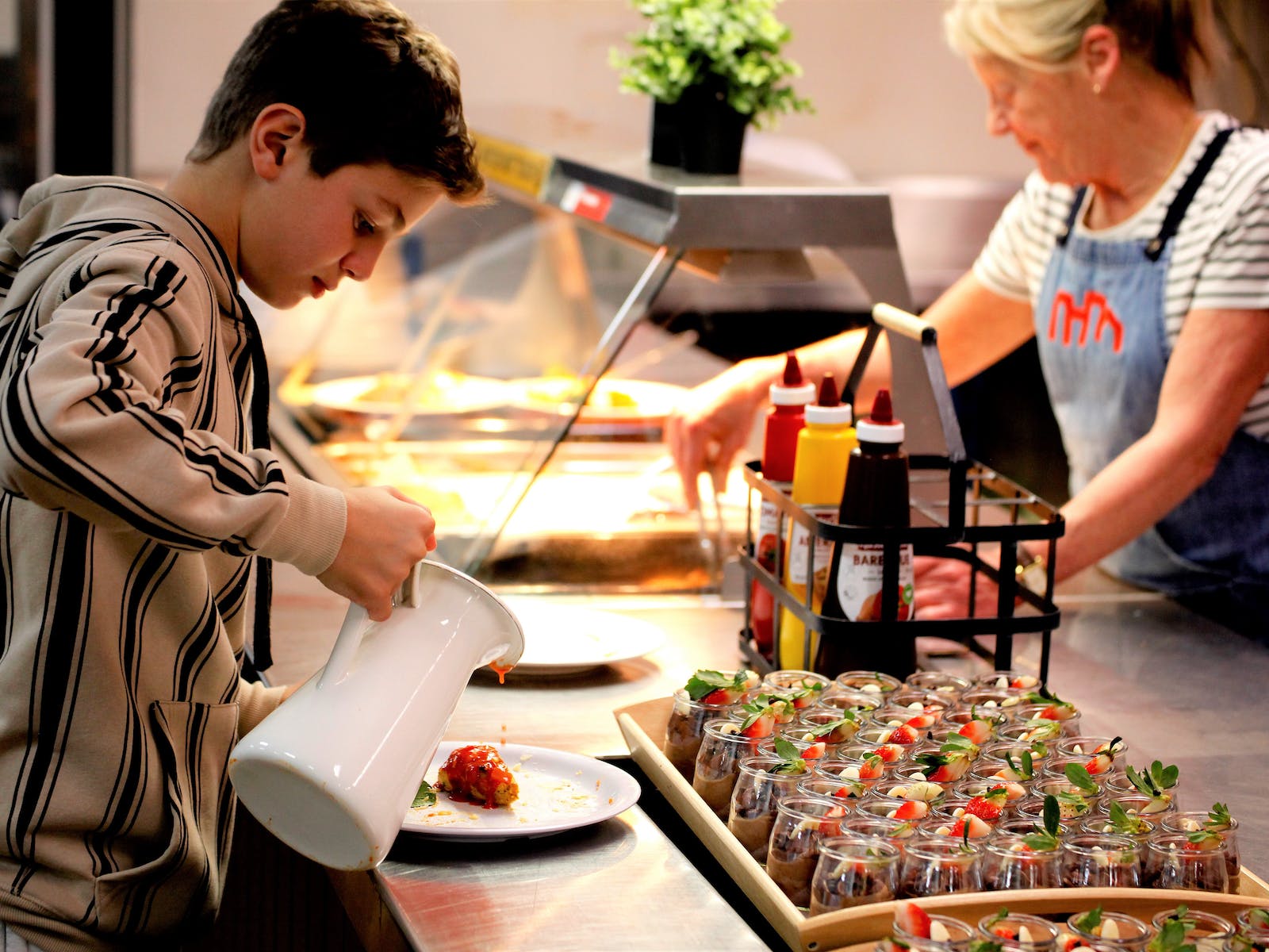 Student pouring custard over a strawberry at Urban Camp