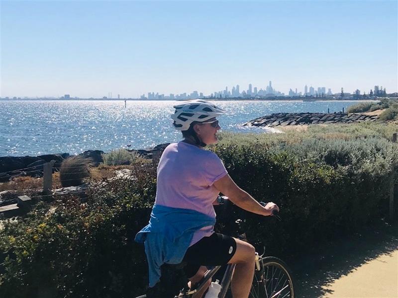 guide allison cycling with guests with view of melbourne sky line on a brighton bayside cycle tour