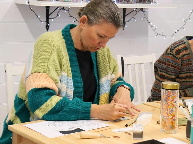 A woman sketching onto lino in the printmaking workshop